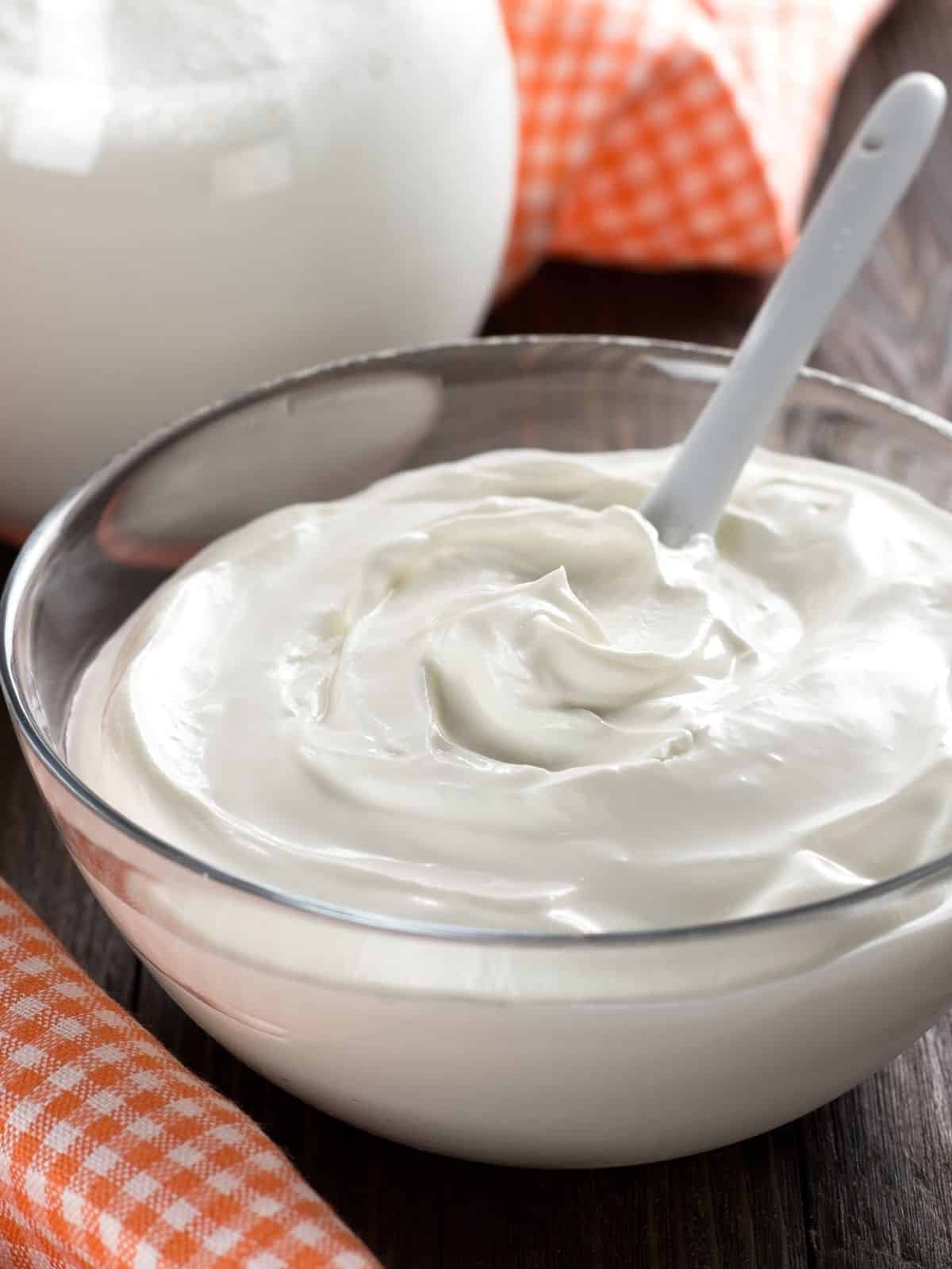 A glass bowl full of sour cream.