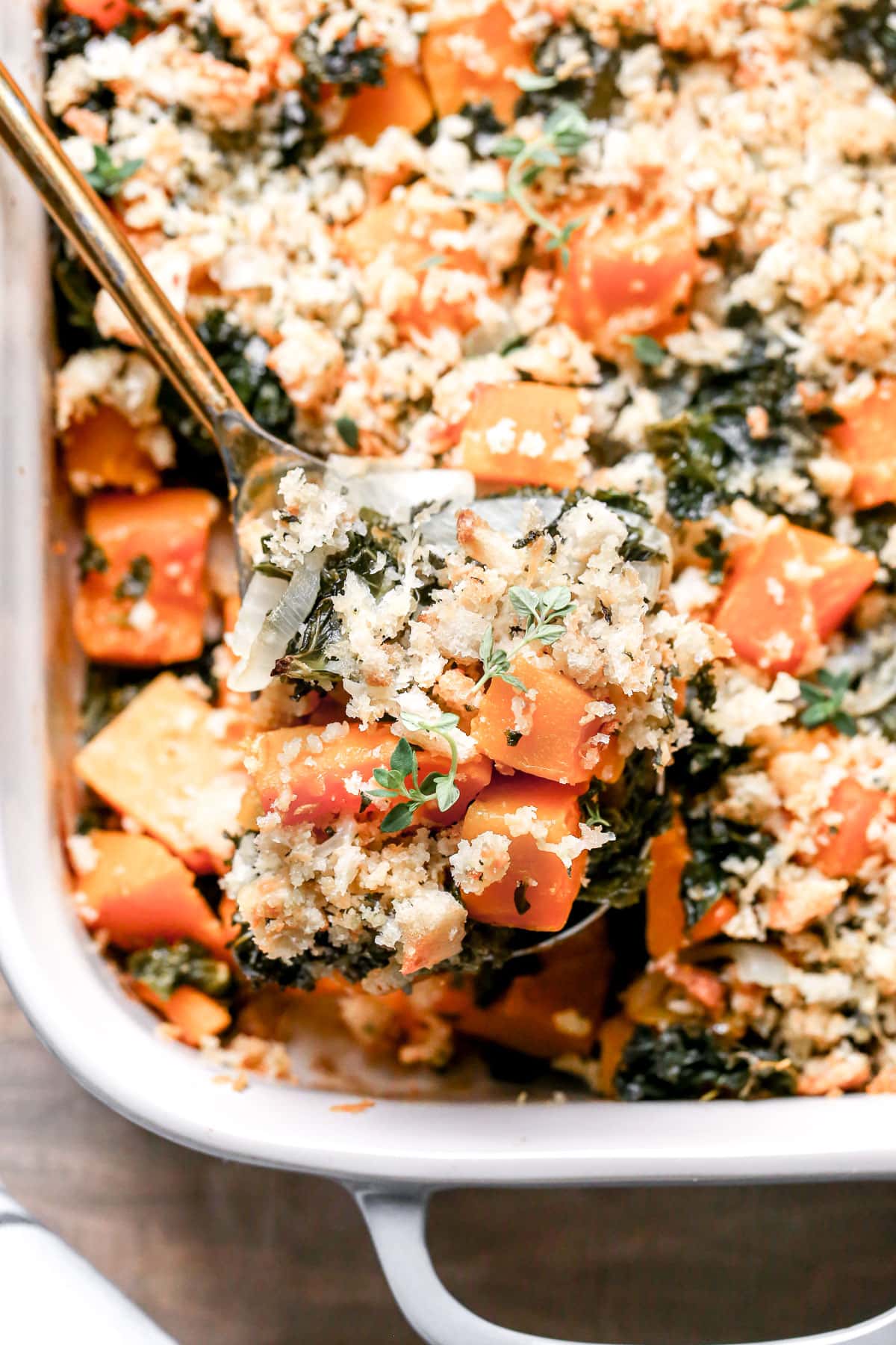 A casserole dish with a butternut squash casserole topped with breadcrumbs.