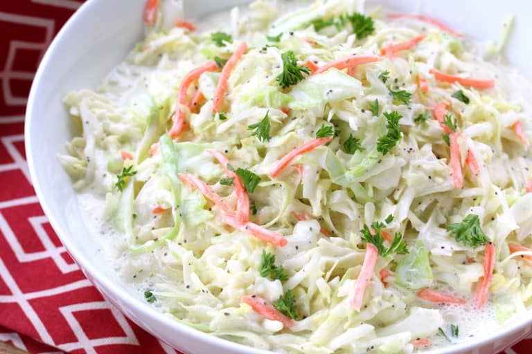A bowl of creamy coleslaw on a table with a red napkin