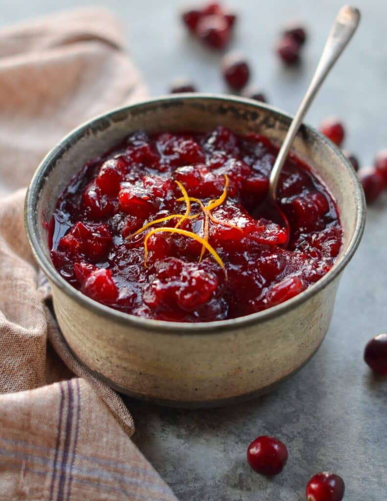 A small bowl of cranberry sauce garnished with orange zest.