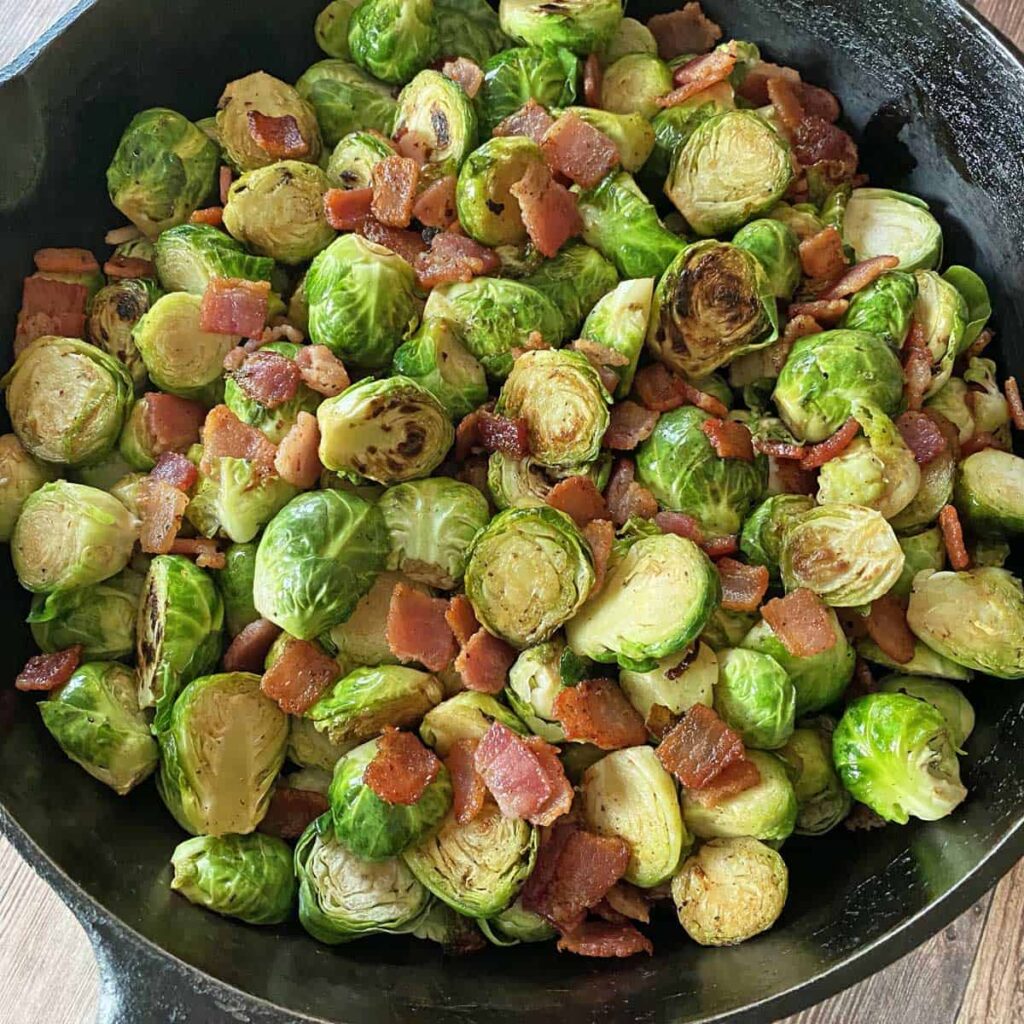 A large cast iron pan with brussels sprouts and bacon.