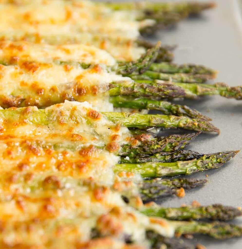 A baking sheet of asparagus cover with broiled cheese. 