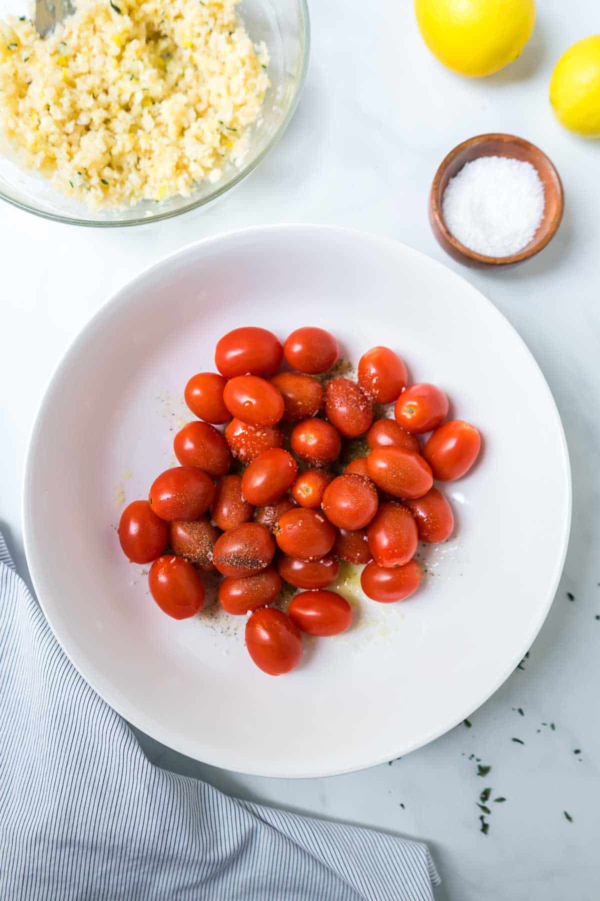 Cherry tomatoes being tossed with olive oil and spices.