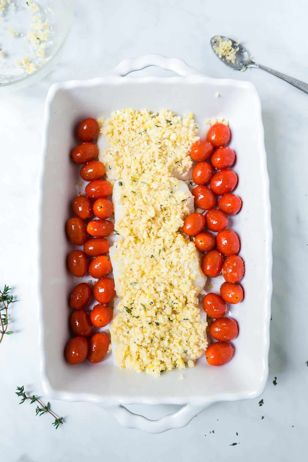 Cod in a white baking dish with cherry tomatoes. 