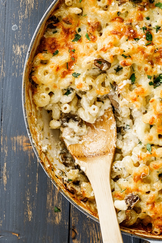 Creamy mushroom pasta bake in a baking dish with a wooden spoon.