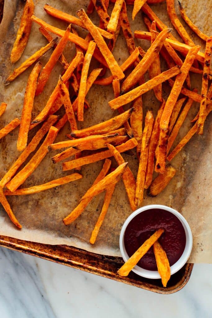 Sweet potato fries on a baking sheet with parchment paper. 