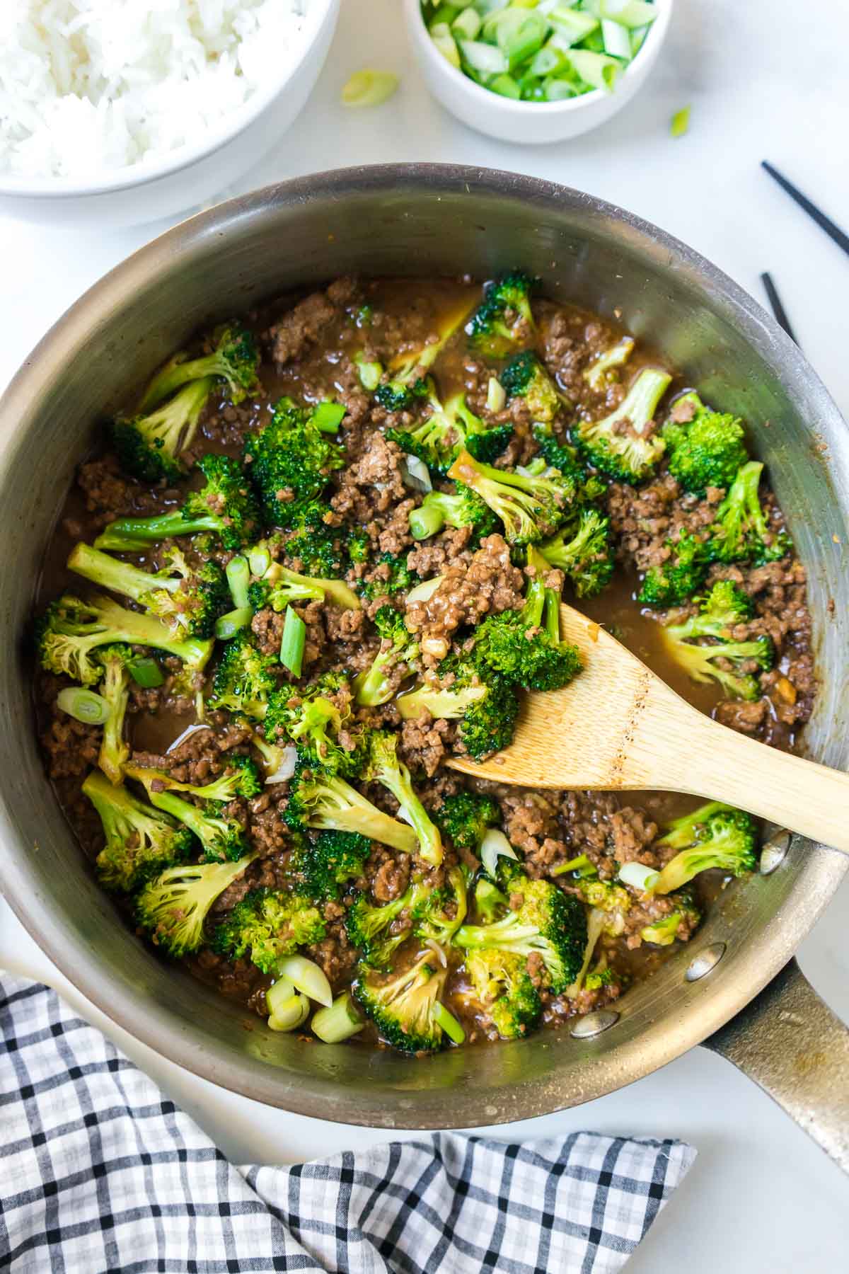 Healthy ground beef and broccoli in a pan with a wooden spoon.