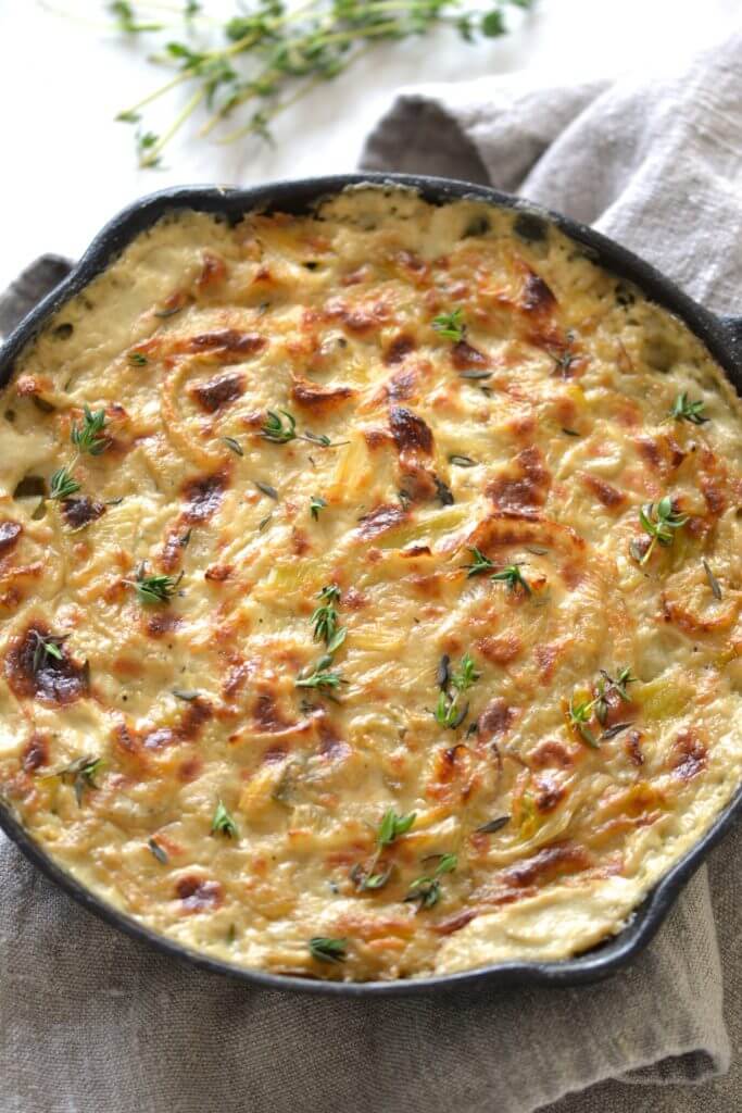 Fennel and Leek gratin in an iron skillet topped with lots of cheese. 