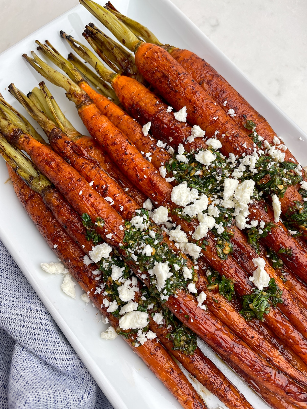 A plate of whole-cooked balsamic glazed carrots topped with feta cheese.