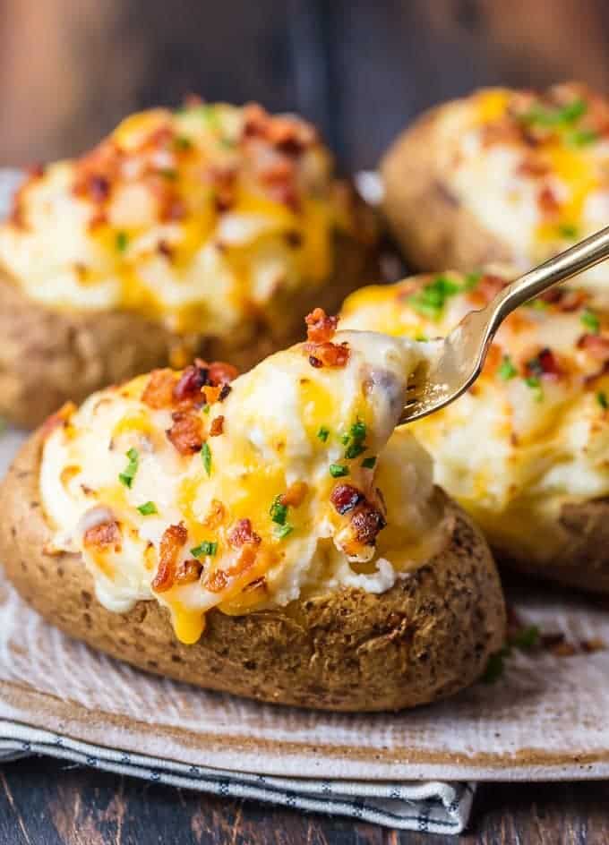 Cheesy twice baked potatoes on a plate with a spoon.