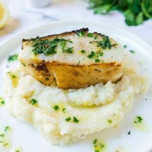 Pan Seared Chilean sea bass on a plate with mashed potatoes.