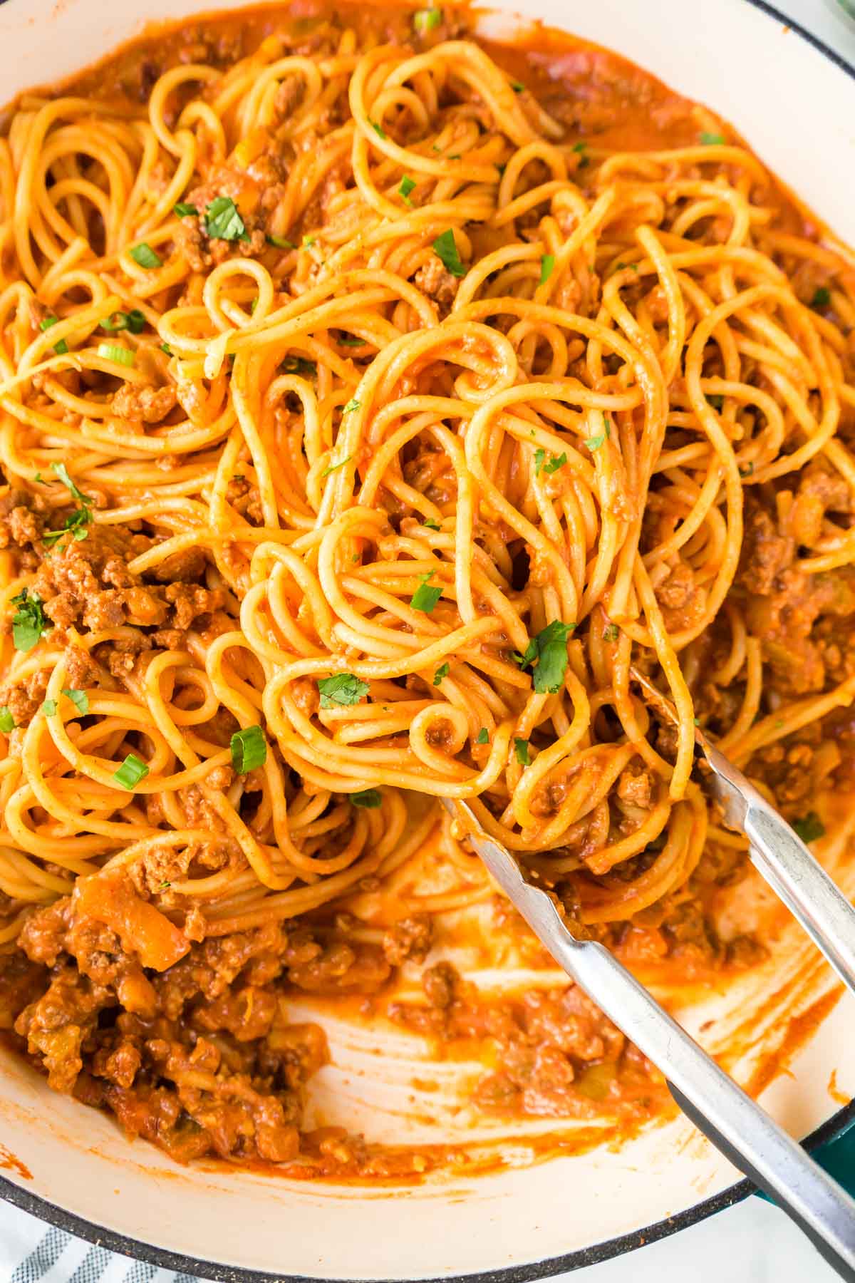 Close up of taco spaghetti being served with tongs.