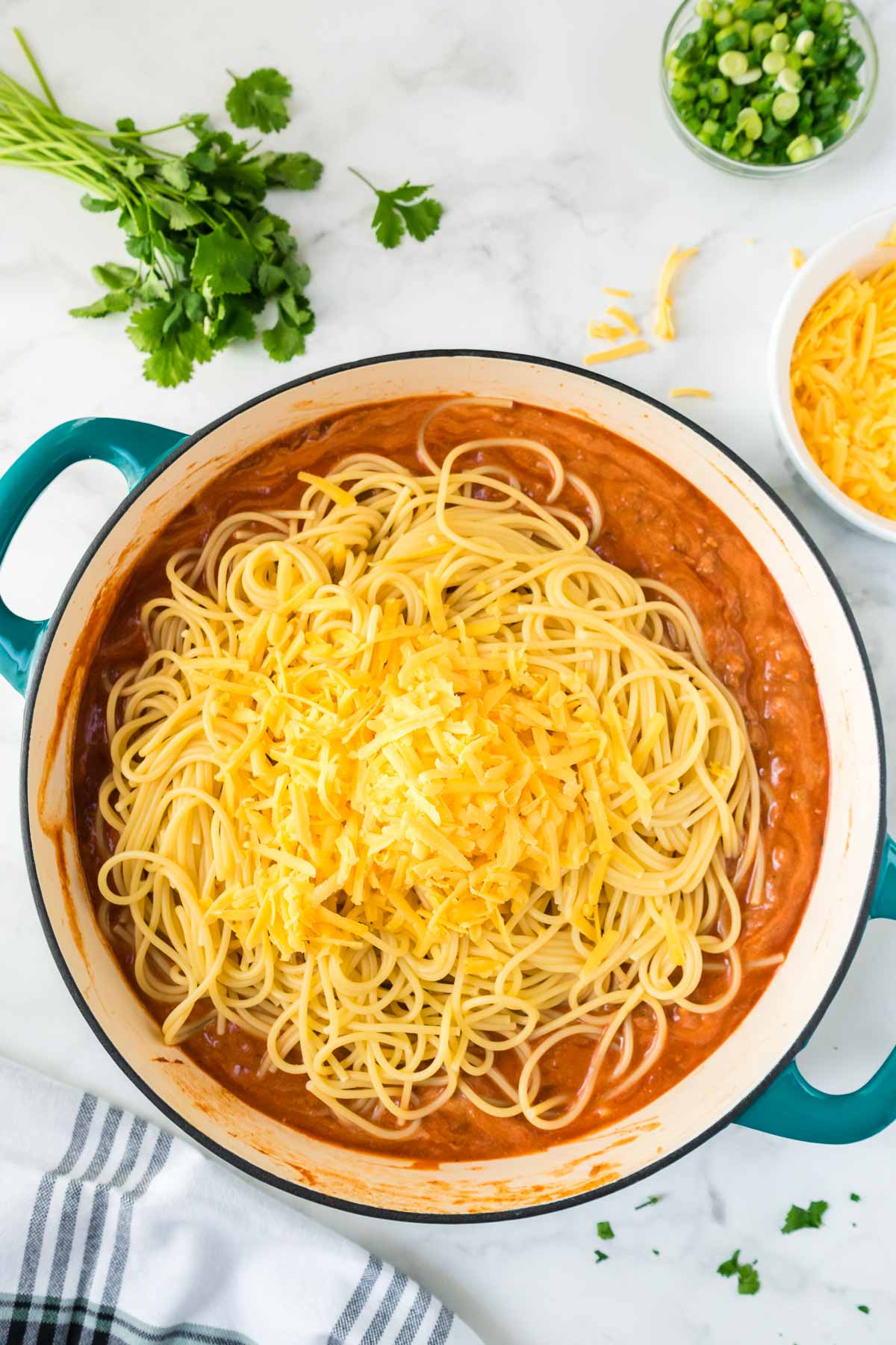 Pan of sauce being tossed with noodles and cheese.