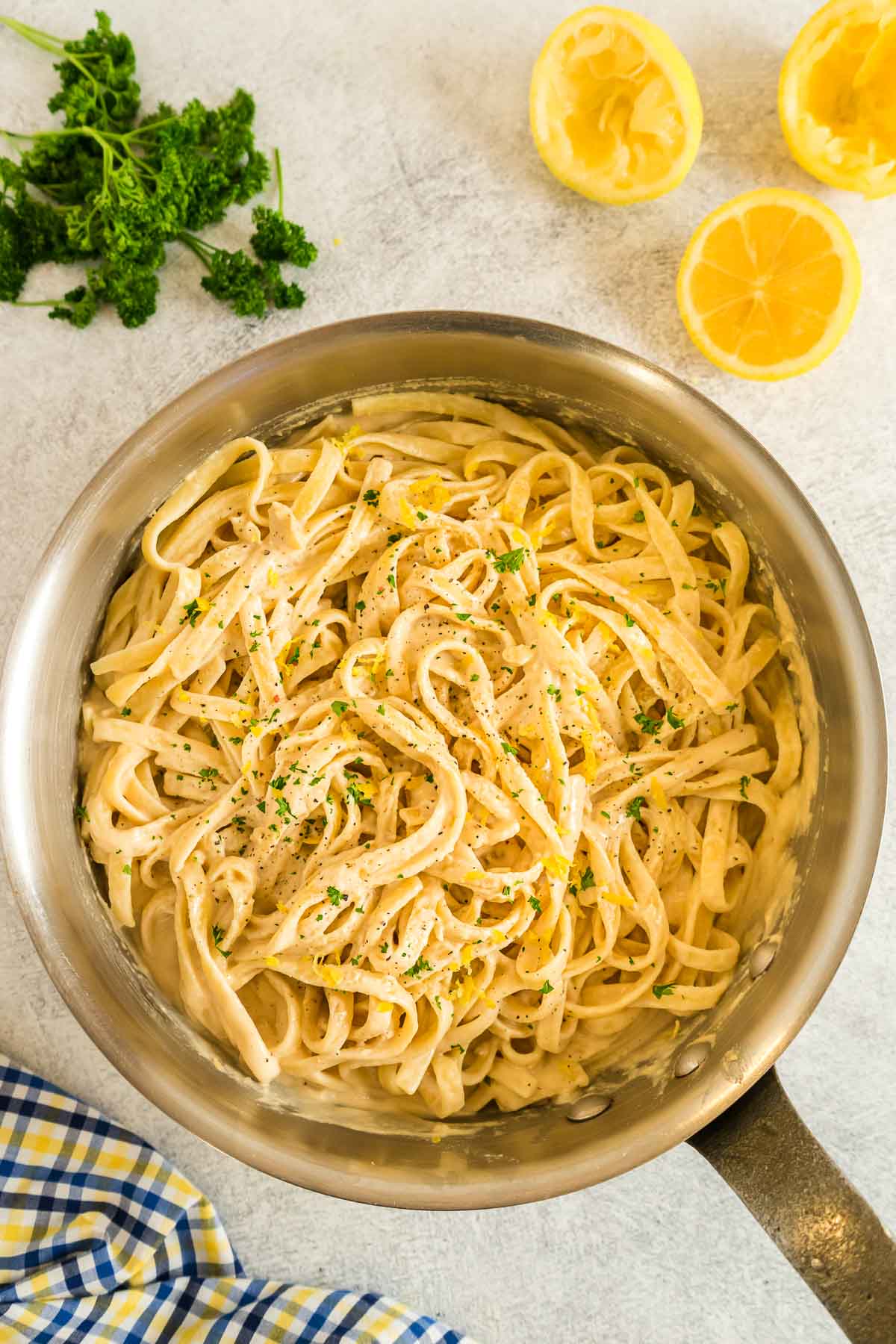 Creamy tahini pasta in a skillet garnished with parsley and lemon zest.