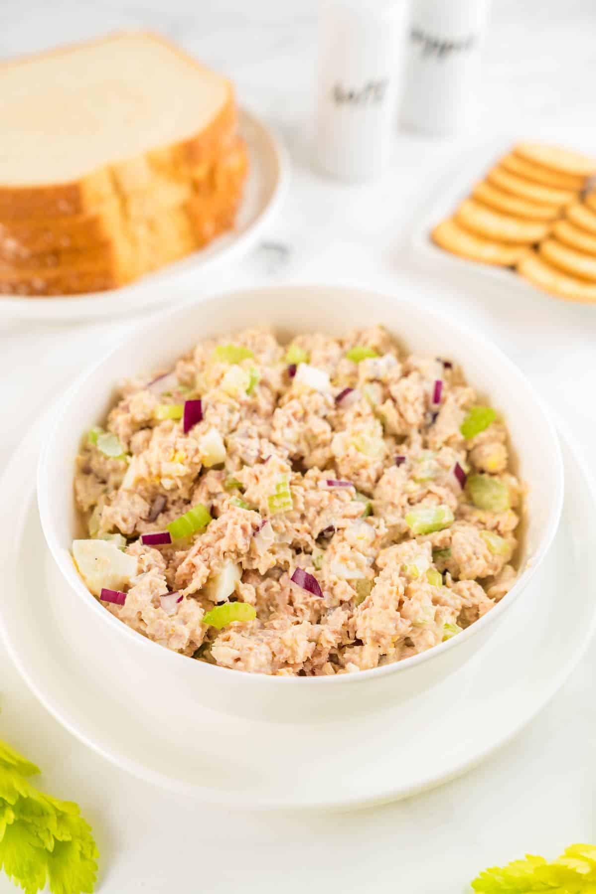 A white bowl of old fashioned ham salad with bread and crackers. 