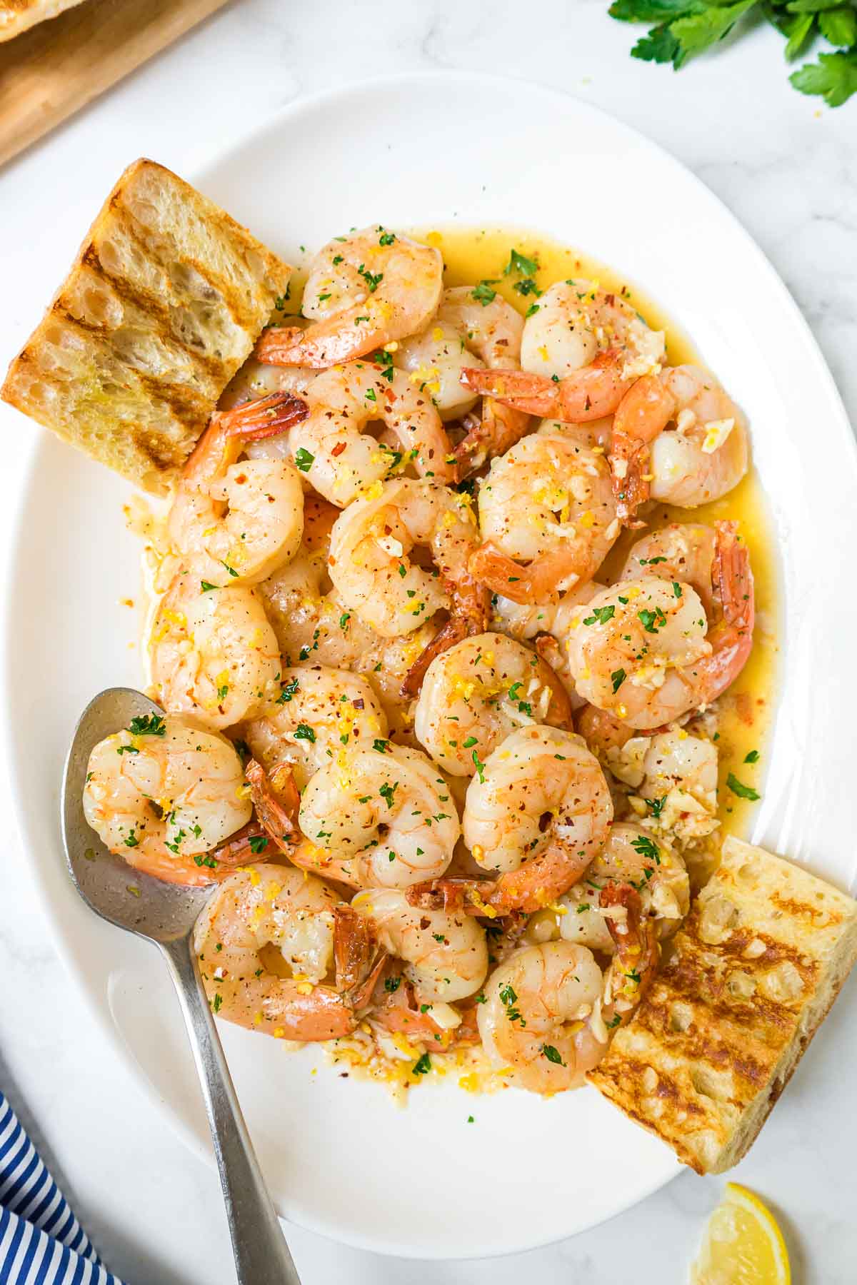 Easy shrimp scampj on a white plate with bread.