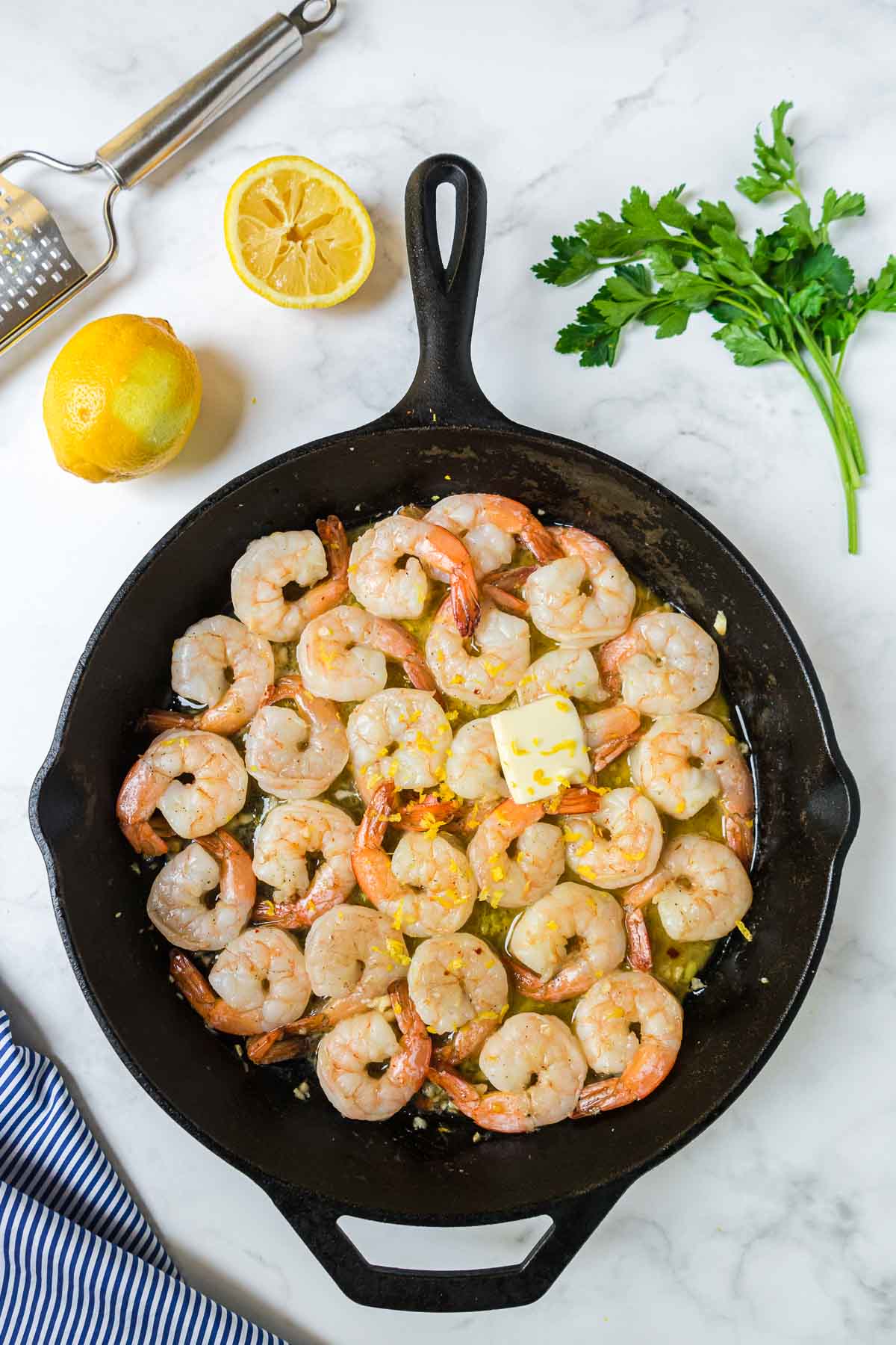 Cooked shrimp scampi in an iron skillet with butter and lemon added.