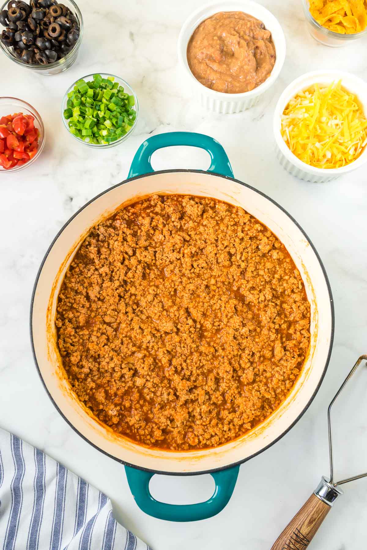 Ground turkey, taco sauce and taco seasoning being cooked in a pan.