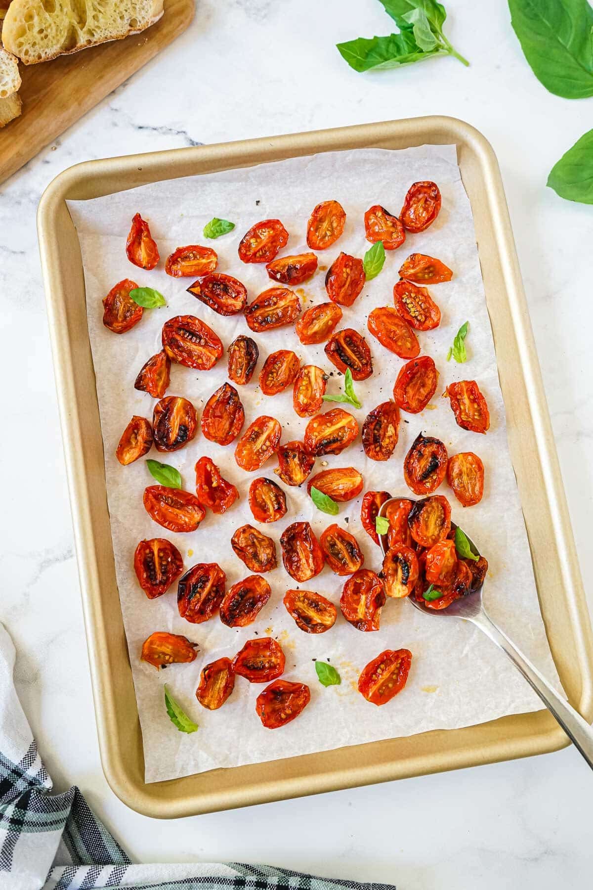 Air Fryer Roasted Tomatoes on a baking sheet with fresh basil. 