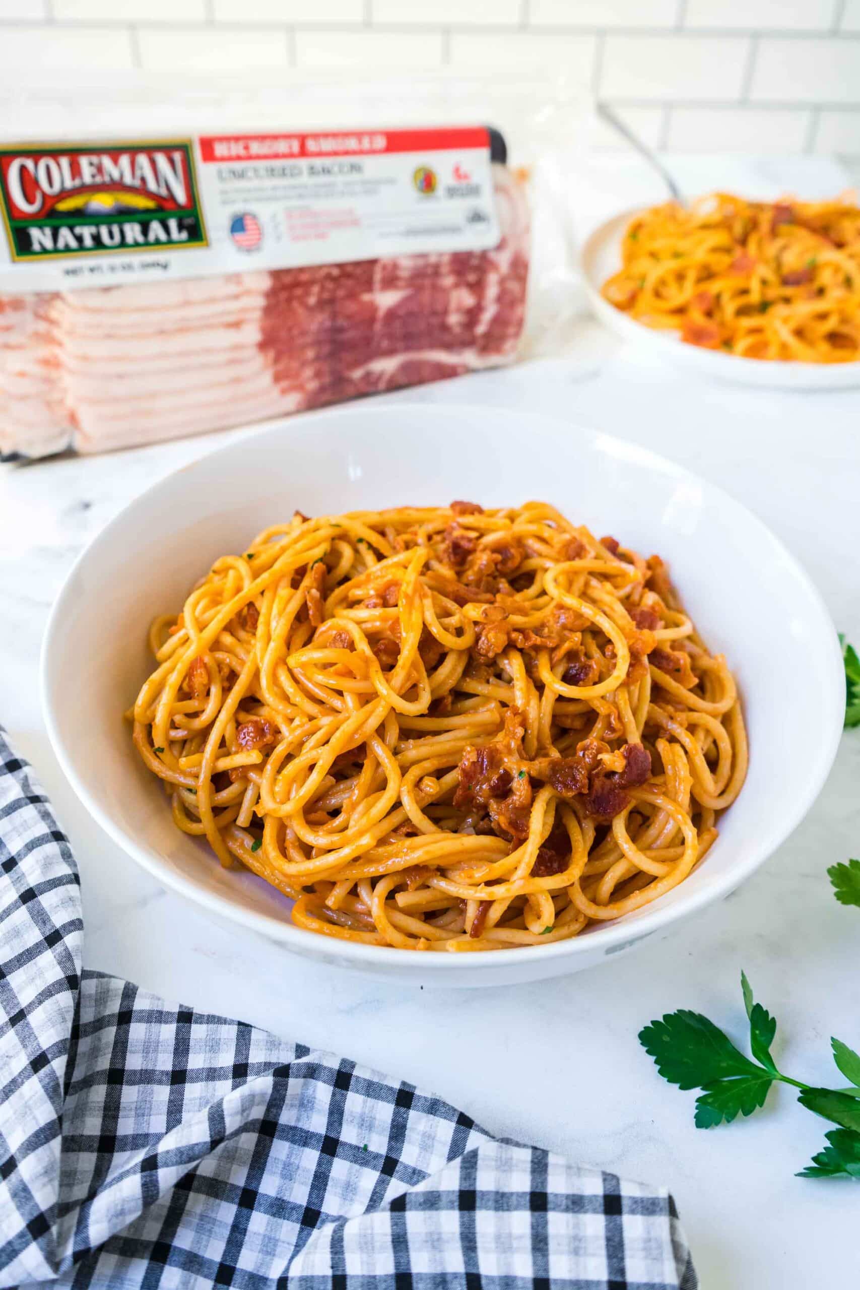 A bowl of Creamy Spaghetti with Bacon with the Coleman Natural Bacon package in the background.