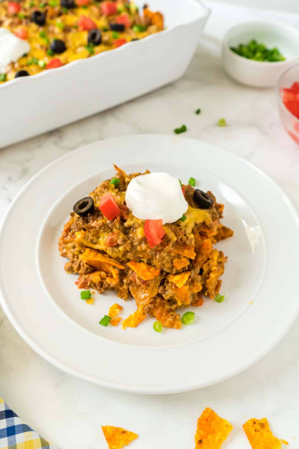 A plate of Dorito Casserole with ground beef topped with sour cream.