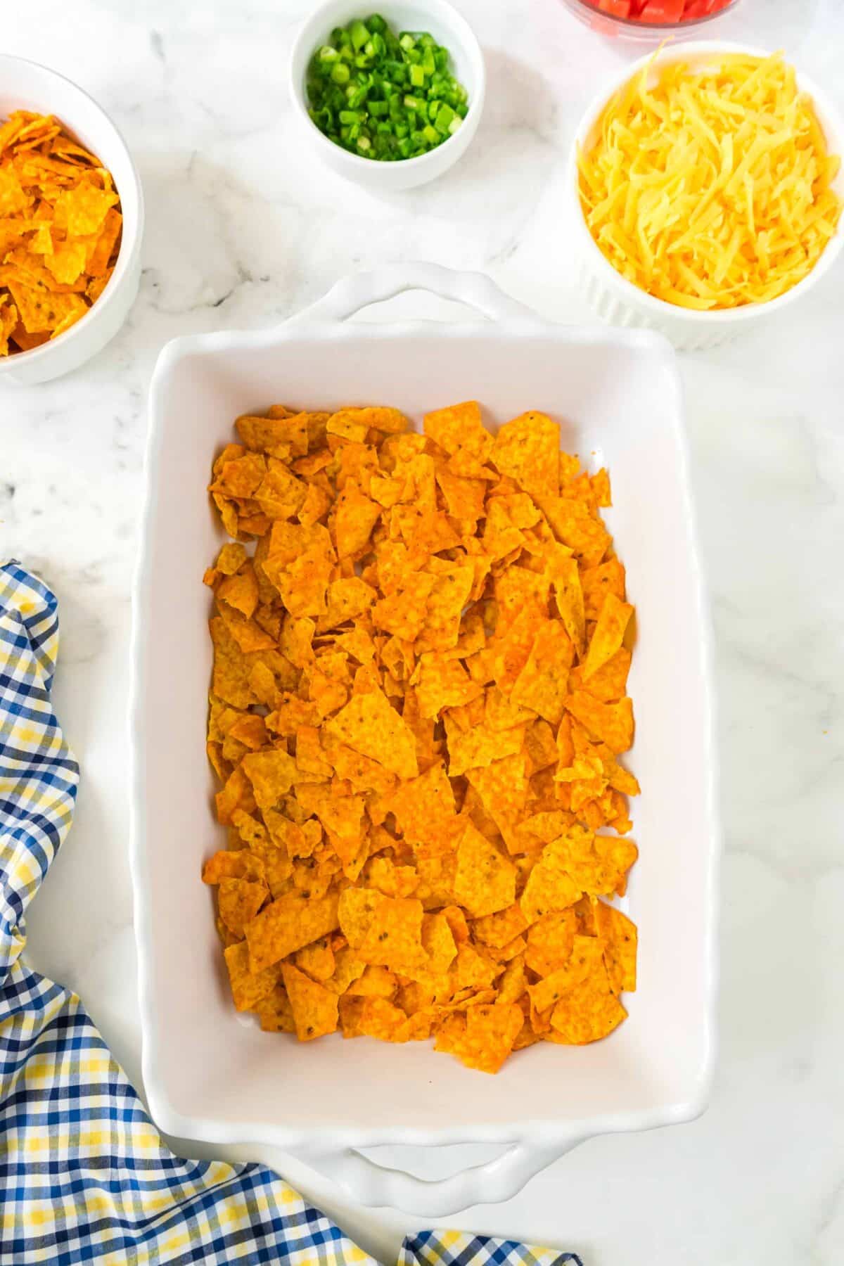 Crushed Doritos chips in a casserole dish.