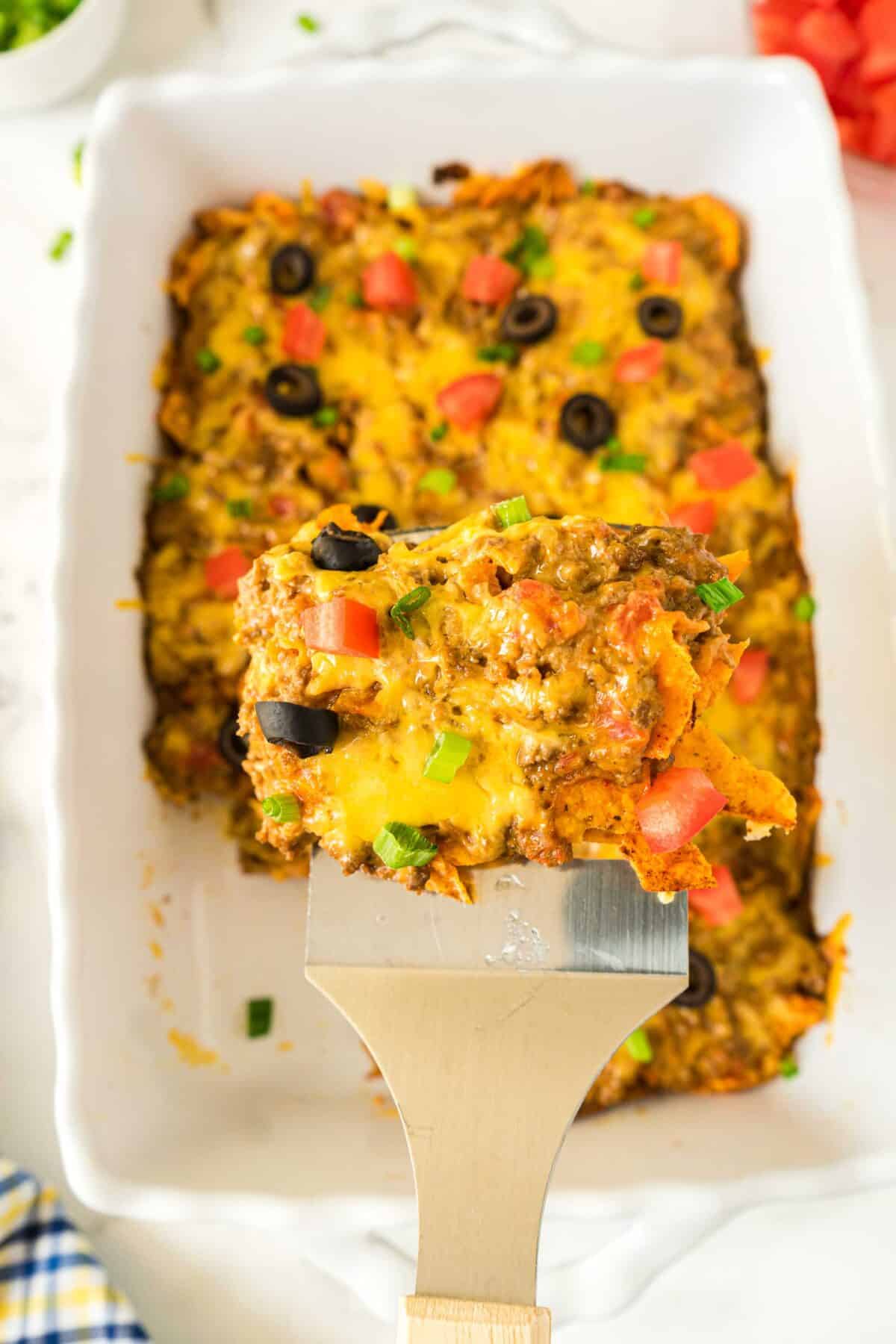 Close up of a piece of Dorito casserole with ground beef on a spatula.
