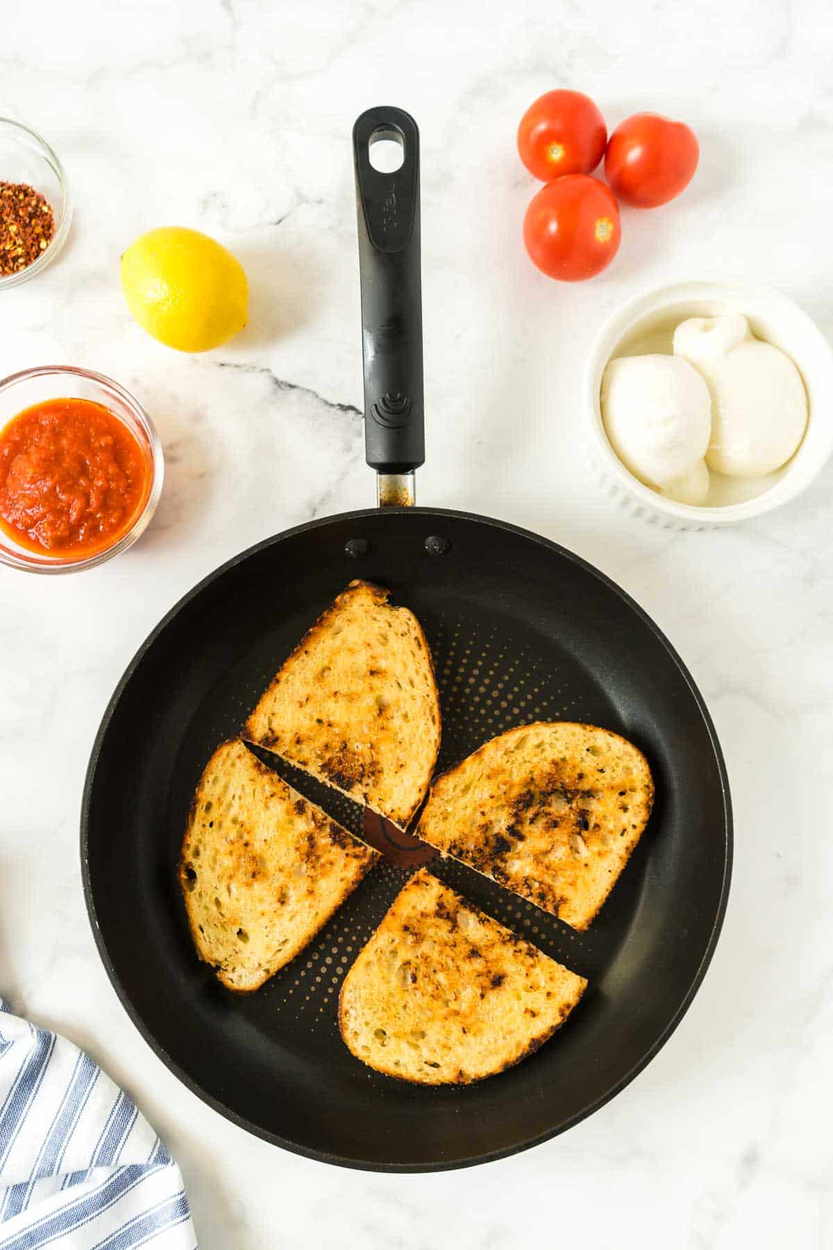 Bread toasting in a black skillet to make the viral pizza toast recipe.