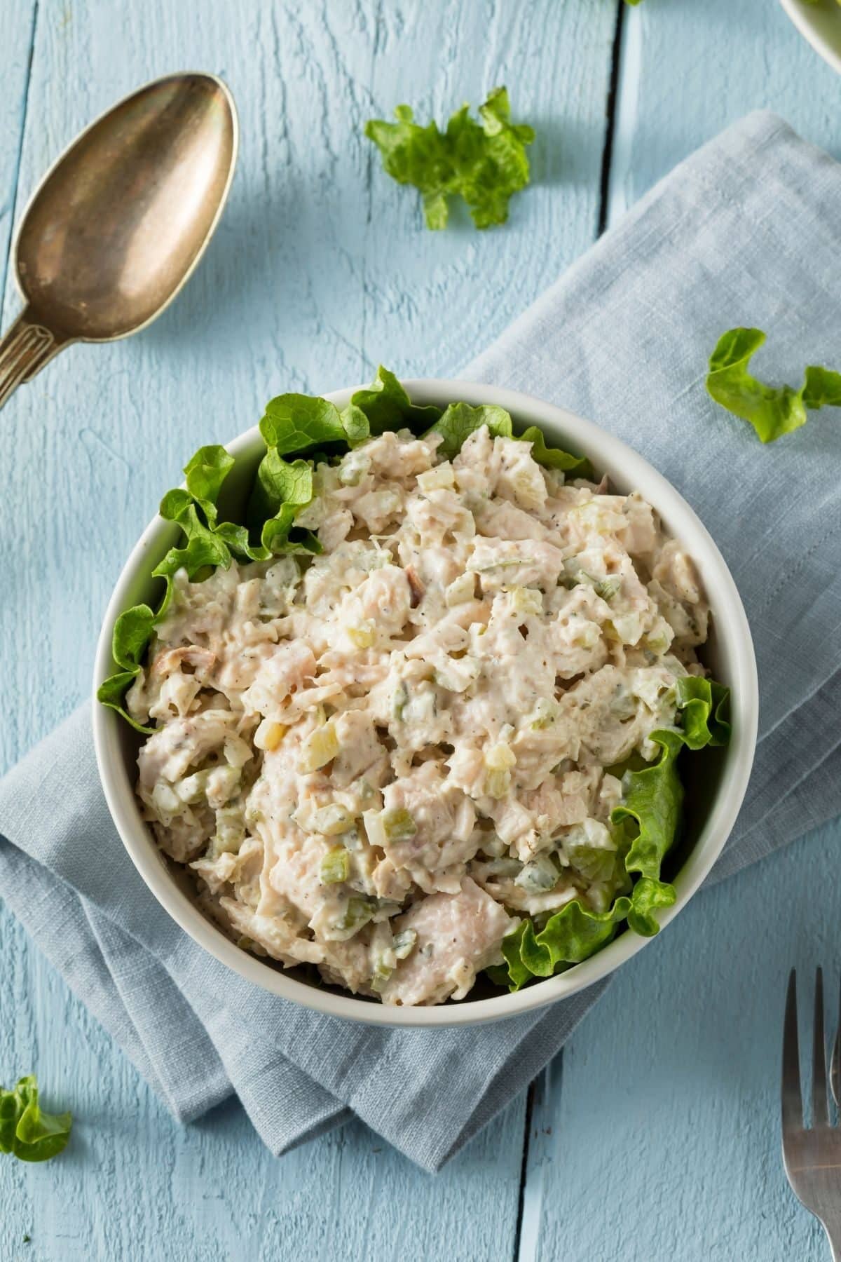 Classic homemade chicken salad in a white bow, with lettuce.