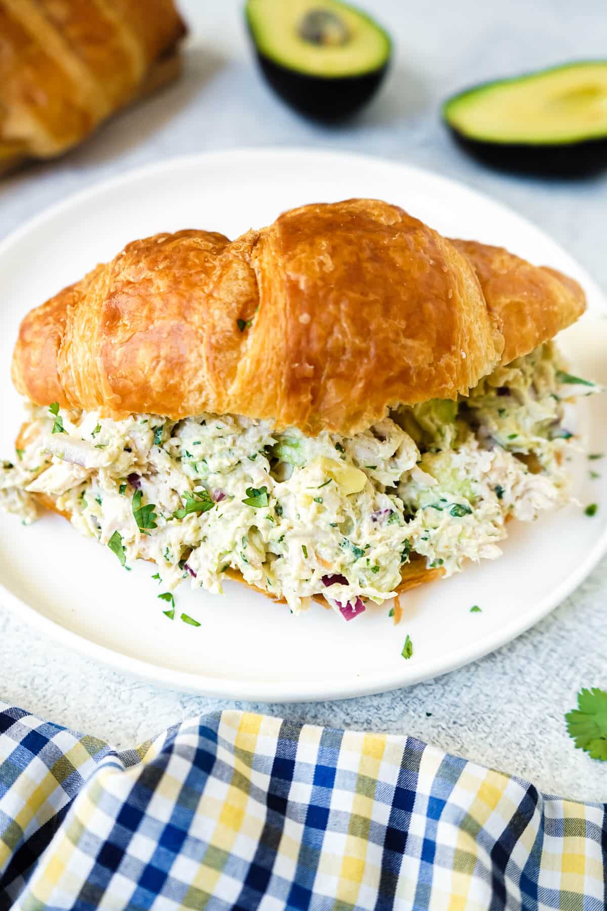 California Chicken Salad sandwich on a croissant sitting in a white plate.