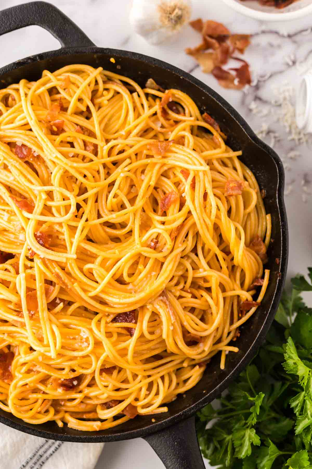 Creamy spaghetti with bacon in a cast iron skillet.