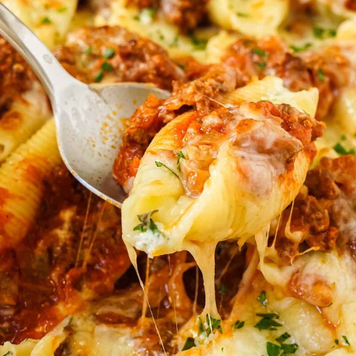 Cheesy stuffed shells with beef on a spoon.