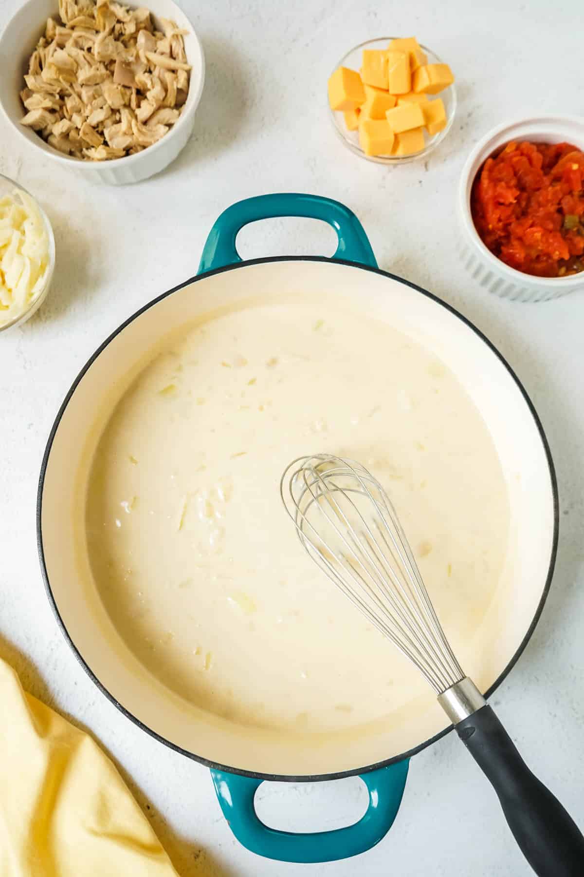 Creamy sauce in a large skillet with a whisk.