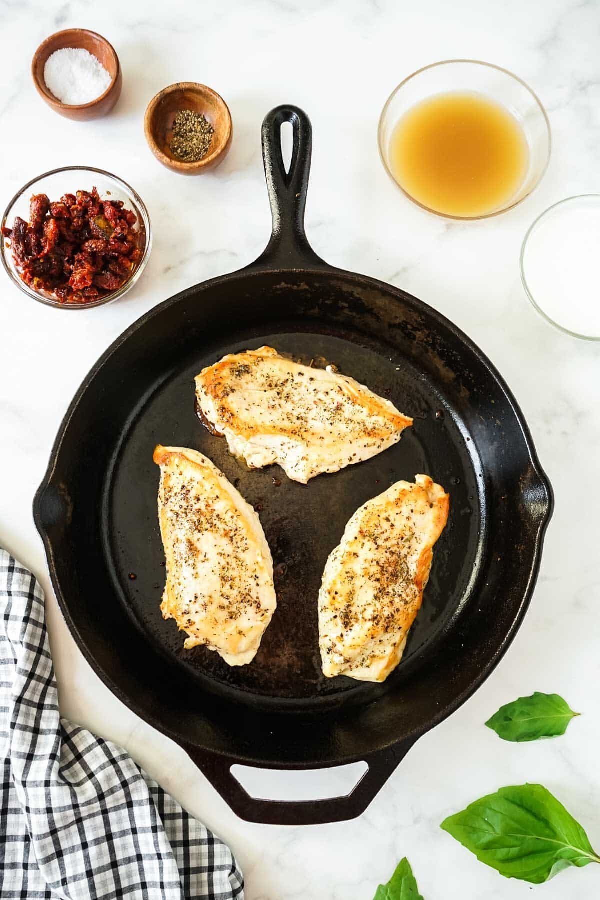 Chicken breasts being cooked in a skillet.