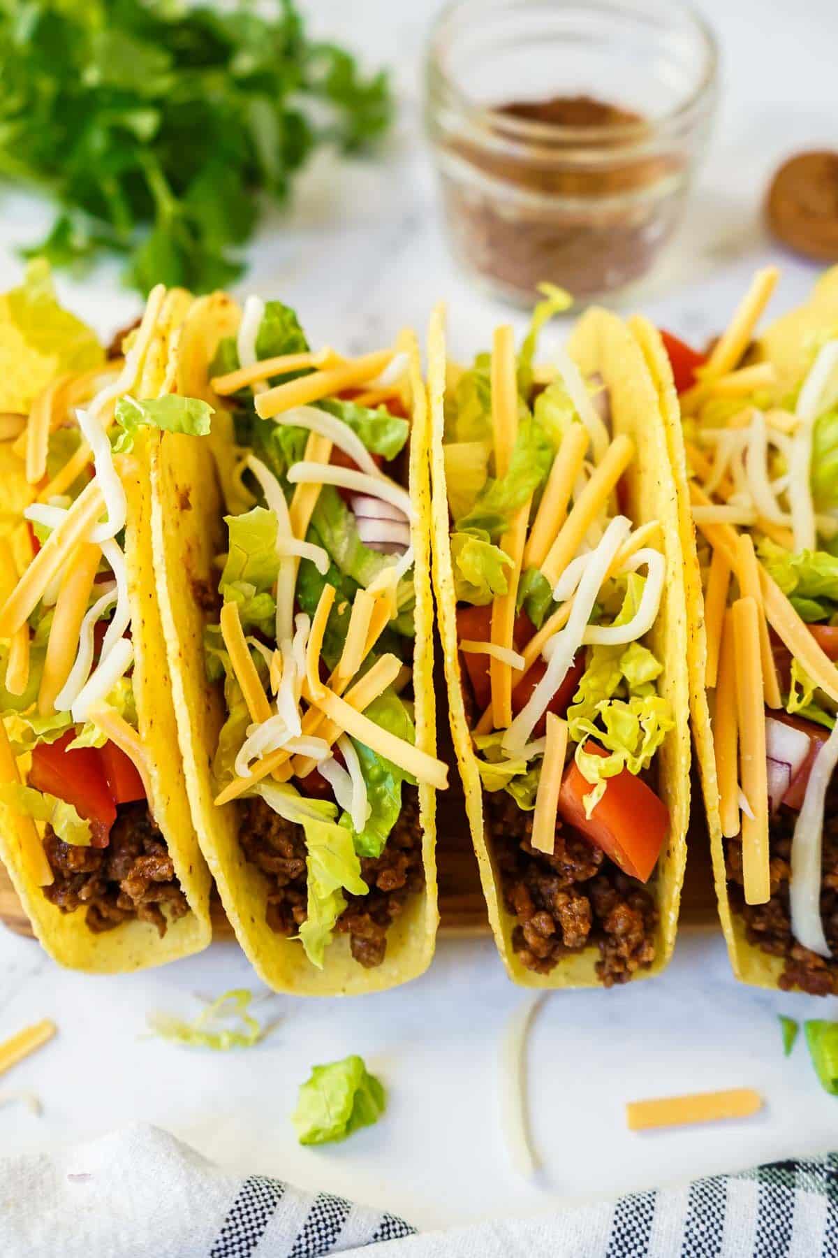 Hard shell ground beef tacos lined up on a plate.