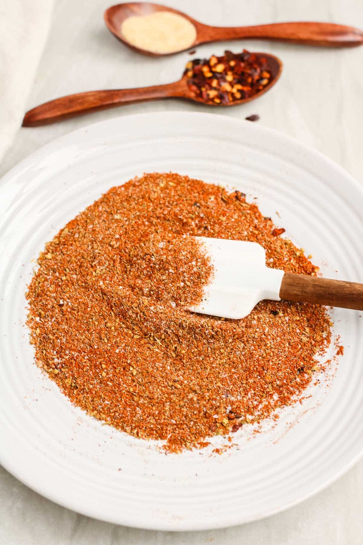 Spices for homemade low sodium taco seasoning on a plate being mixed with a white spatula.
