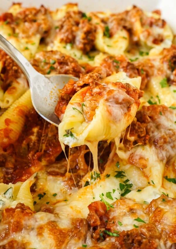 Close up of cheesy stuffed shells with beef on a spoon.
