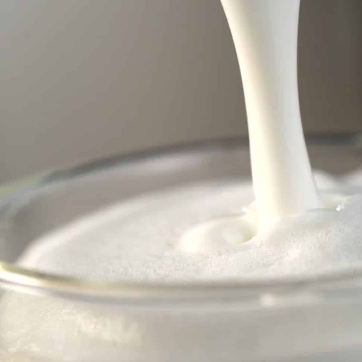 Heavy cream or milk being poured into a glass.