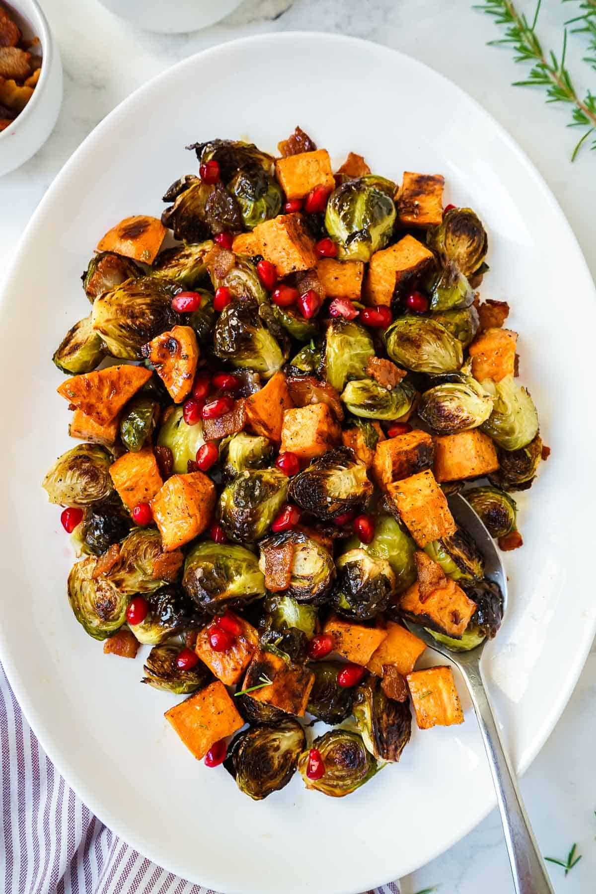 Roasted brussels sprouts and sweet potatoes on a white serving dish.