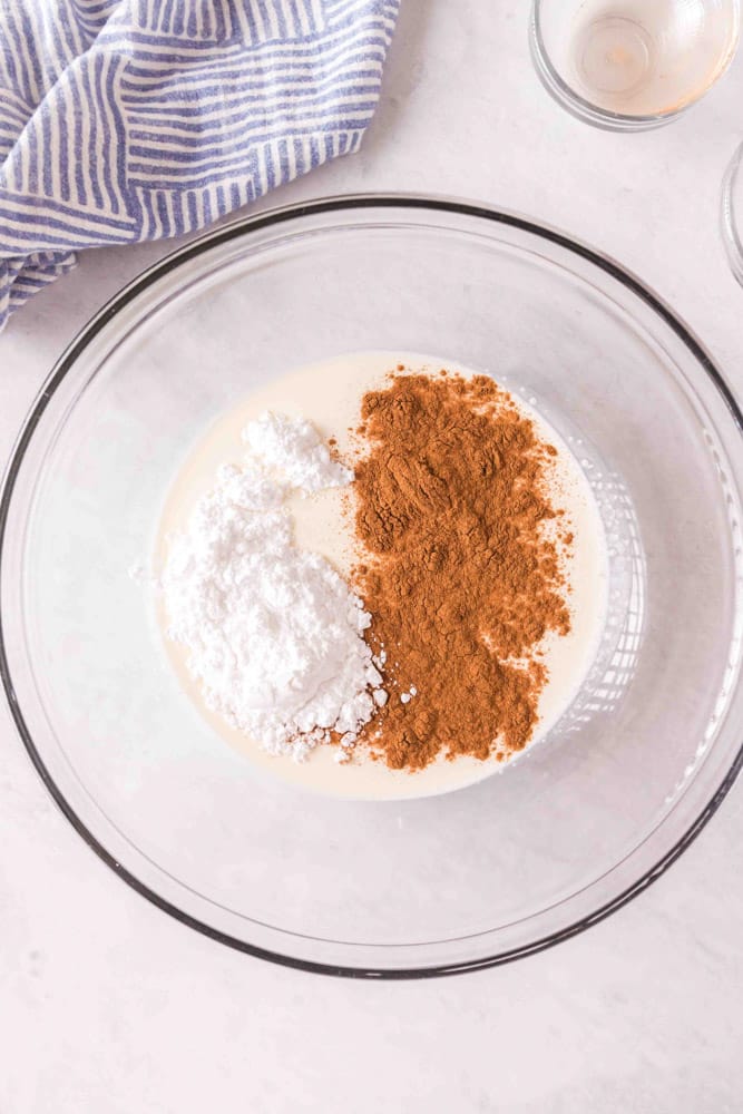 Ingredients to make cinnamon whipped cream in a glass bowl.