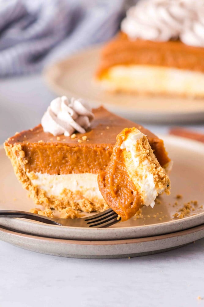 Double layer pumpkin pie on a white plate with a fork.