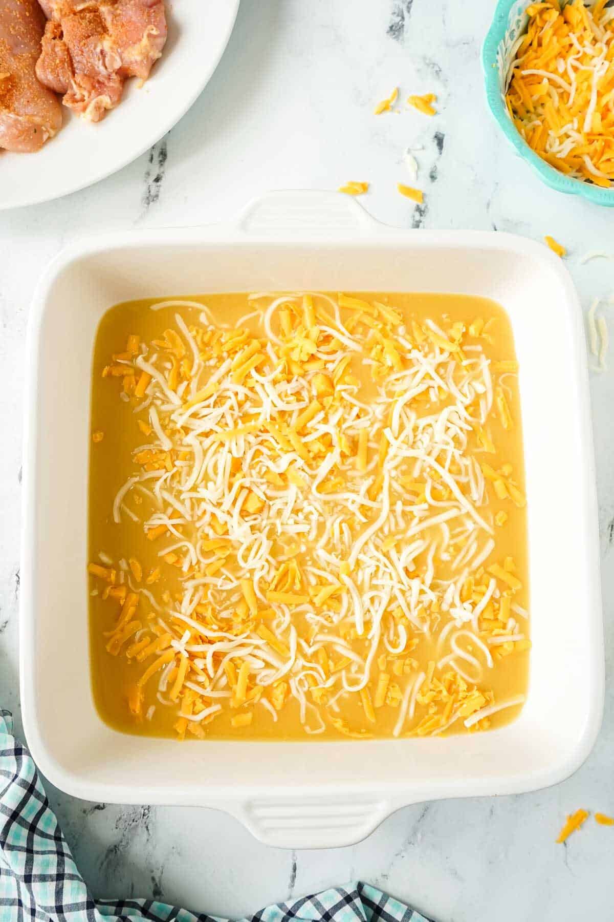 Cream of chicken soup and cheese in a baking dish.