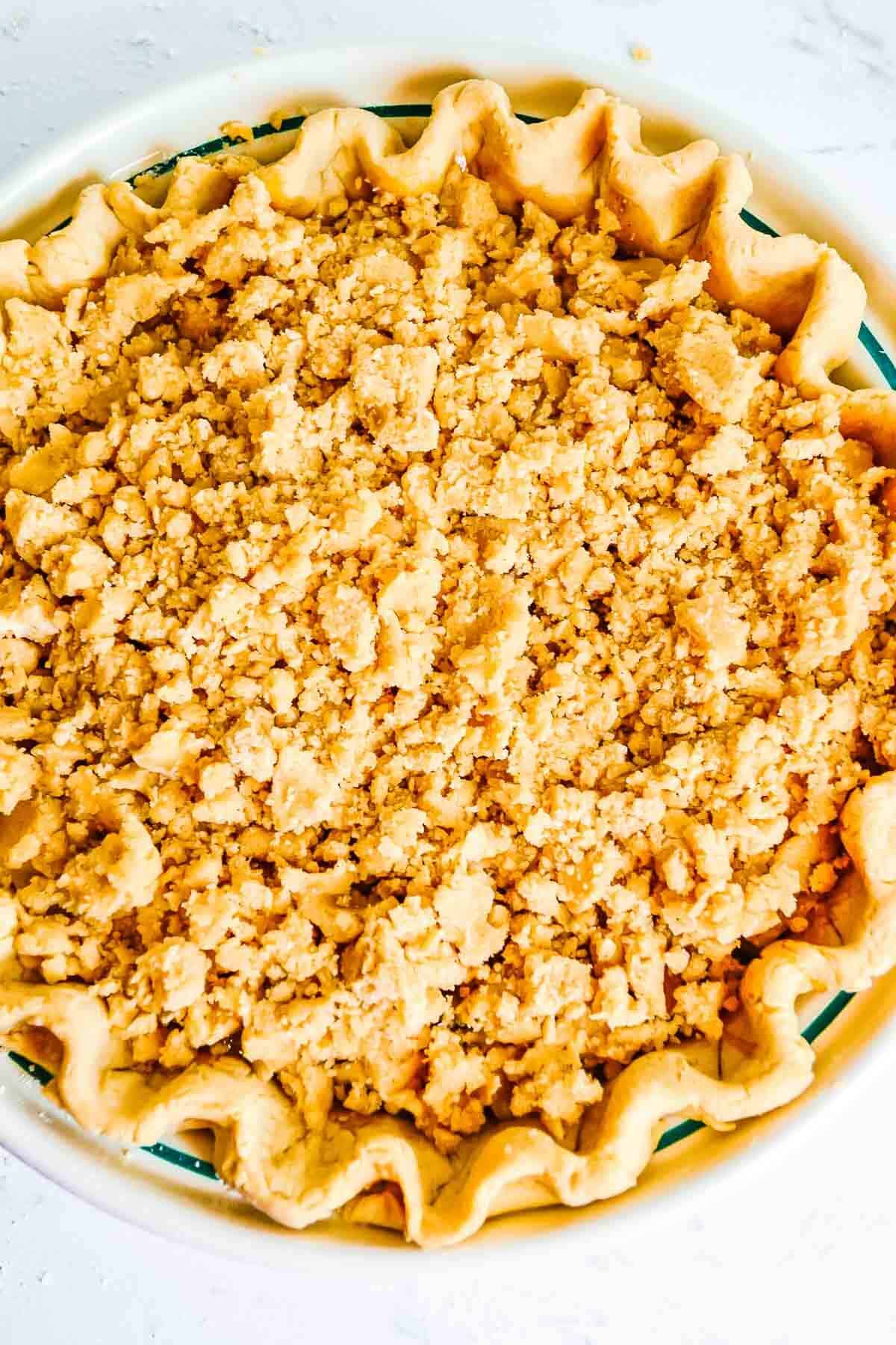 Pie shell filled with caramel apples with the crumb topping before baked.