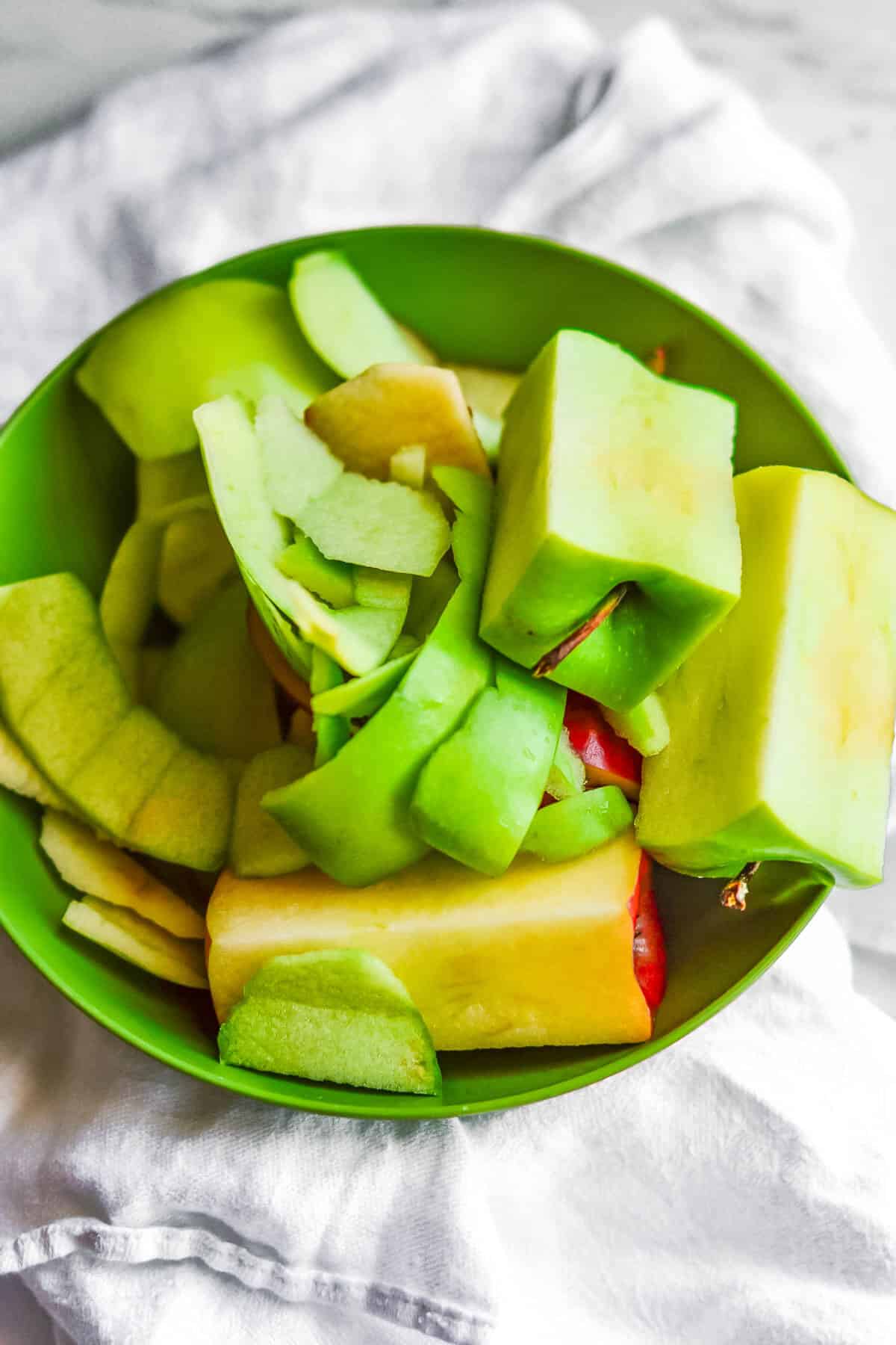 Cores and apple peels in a green bowl.