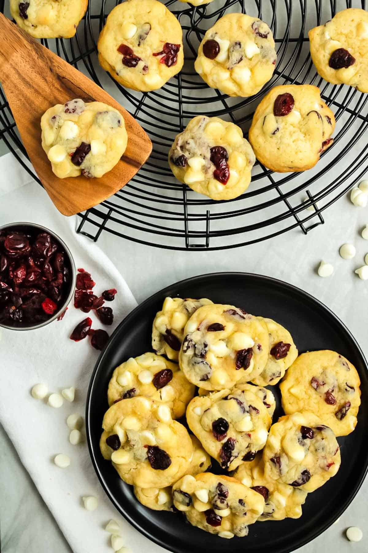 A large plate with White Chocolate Cranberry Cookies with a cooling rack in the background.