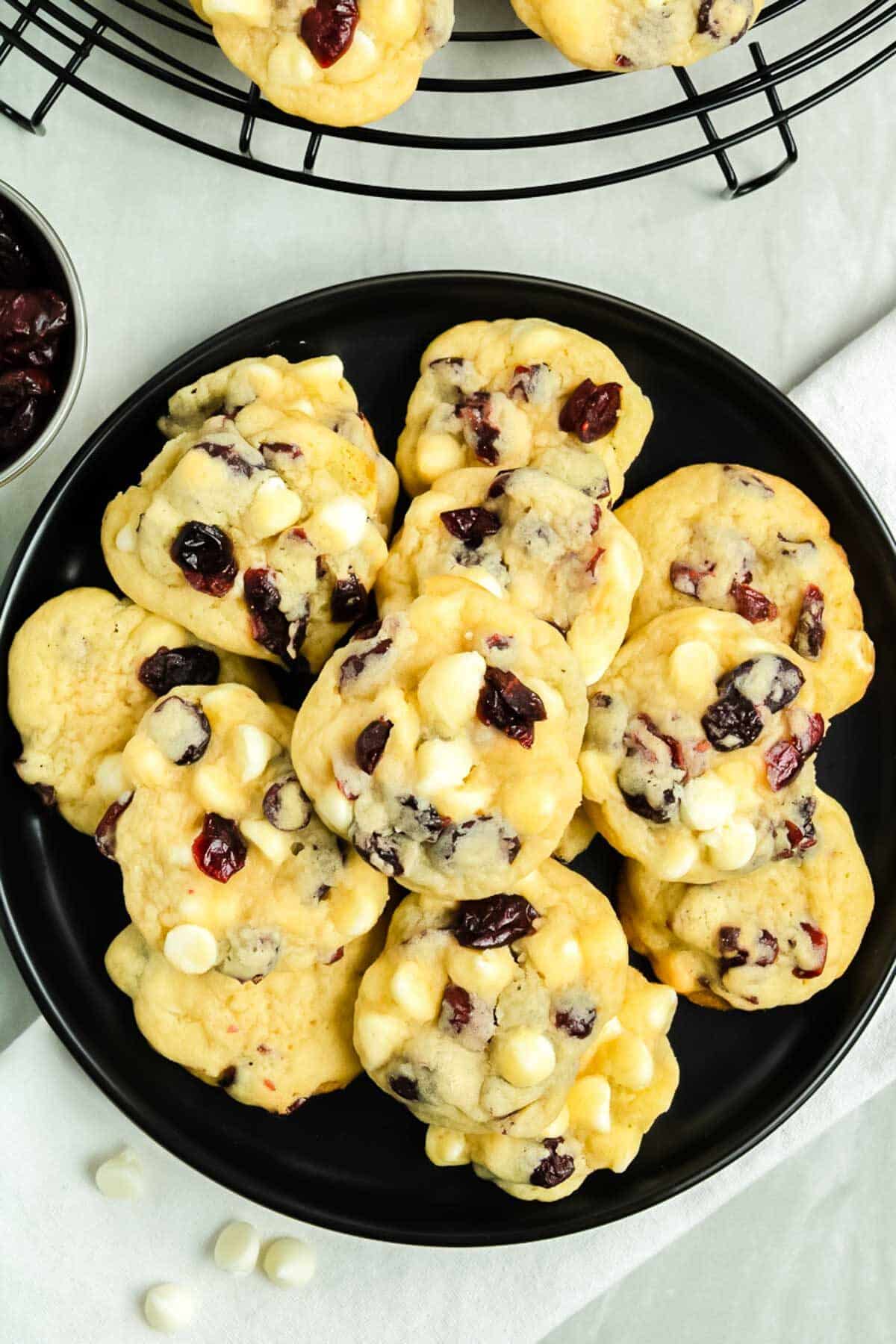 A large black plate filled with White Chocolate Chip and Cranberry Cookies.