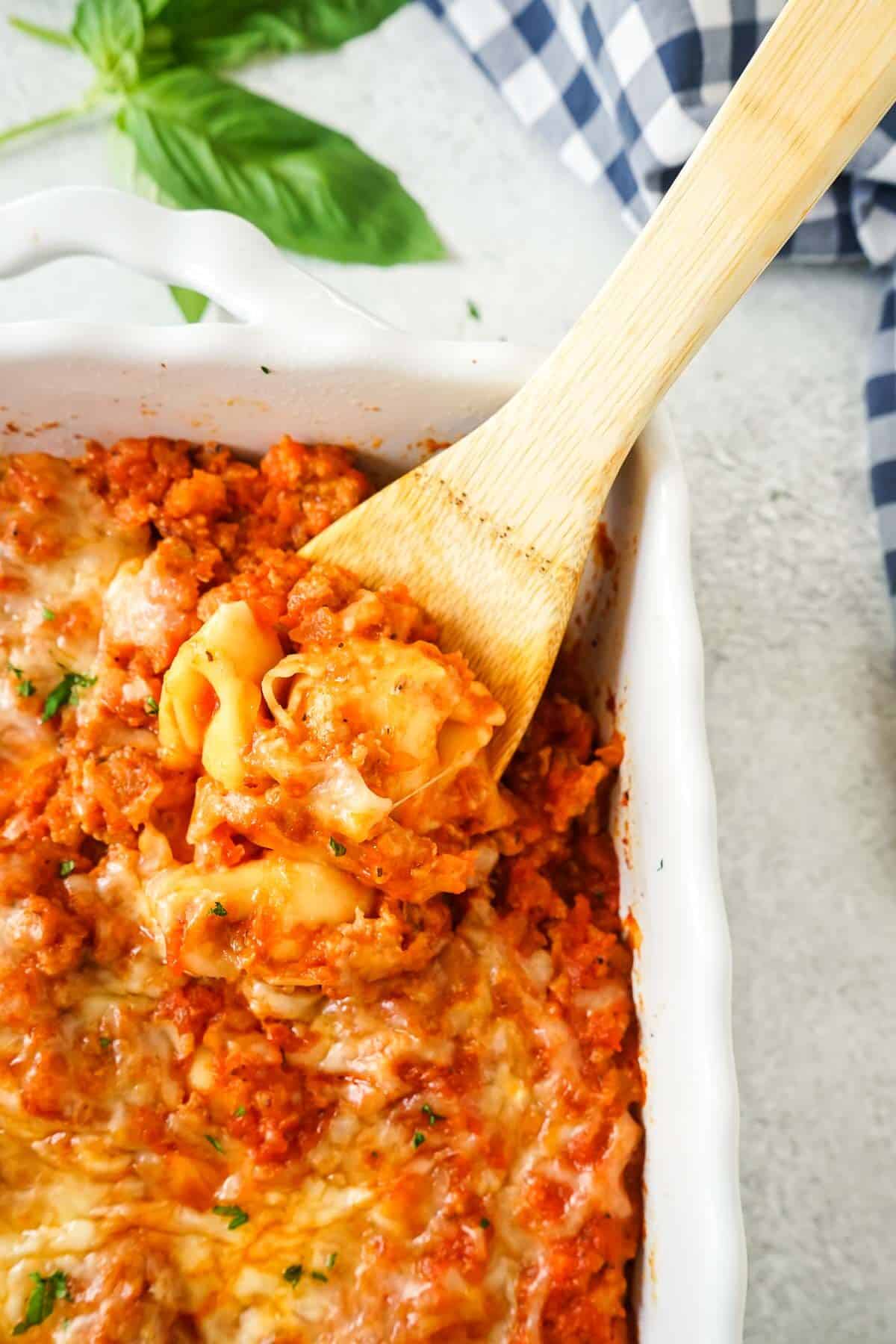 A close up of Easy Tortellini Bake with Sausage on a wooden spoon.