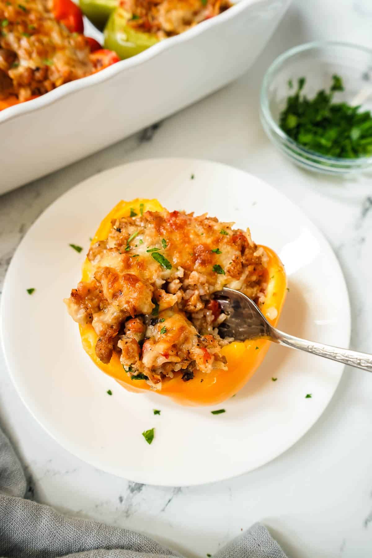 Italian Sausage Stuffed Pepper on a white plate with a fork.