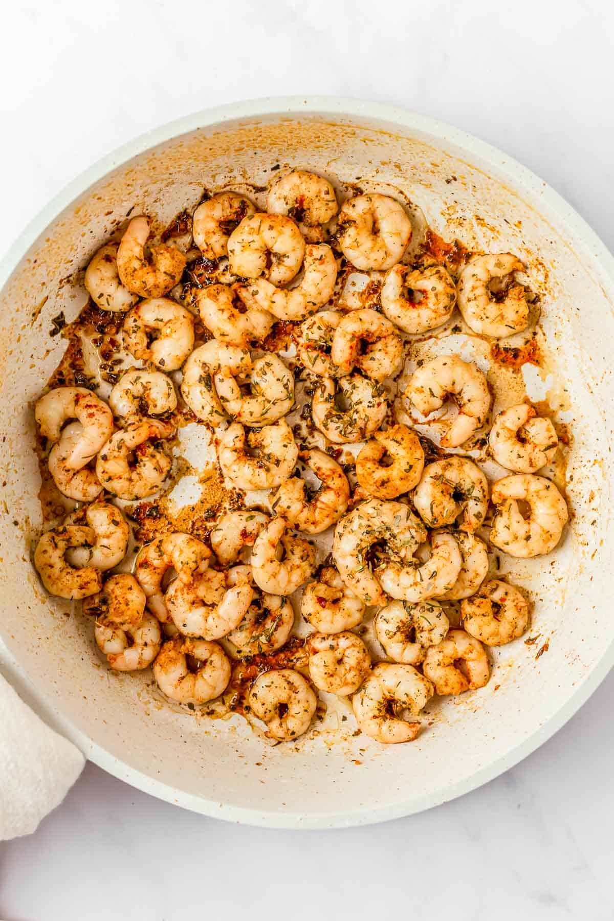 Shrimp with spices being cooked in a large skillet 