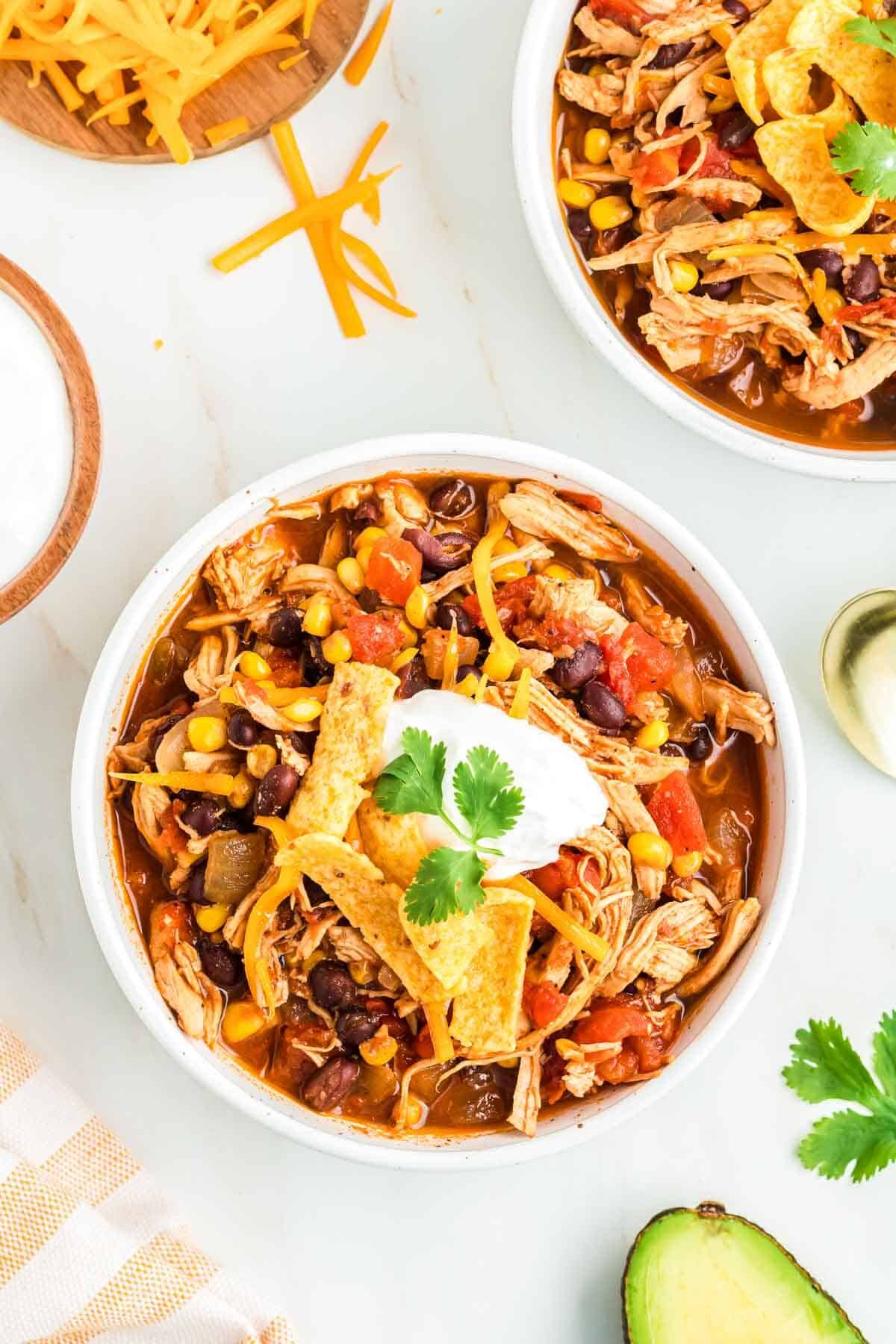 Red chicken chili made with shredded chicken in a bowl, with lots of chili toppings.